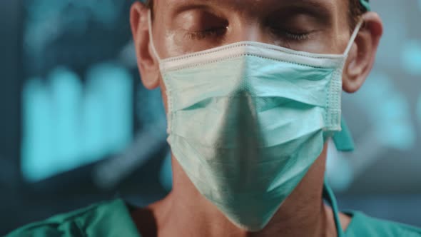 Tired Experienced Male Doctor with Protective Mask on His Face and Surgical Cap