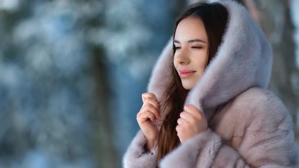 Pretty Lady in Gray Hood Fur Coat at Winter Forest Park