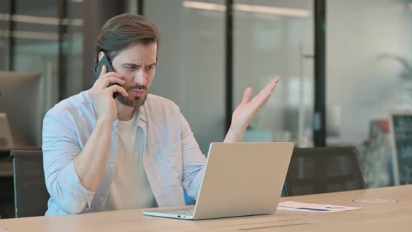 Angry Mature Adult Man with Laptop Talking on Phone