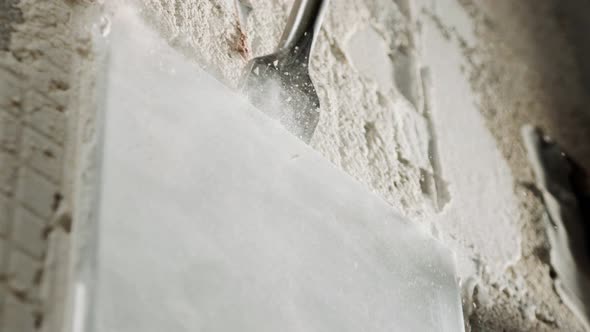 Slow motion of a rotary hammer breaking ceramic tiles off a wall