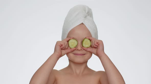 Smiling Child Girl Kid Holding Slices of Cucumber Covering Eyes Natural Cosmetics Face Skin Care