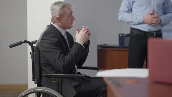 Side View of Confident Handicapped Man Discussing Business Project with Colleagues in Office