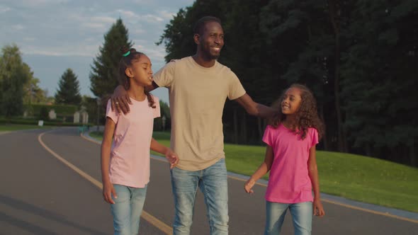 Joyful Father and Two Daughters Relaxing in Park