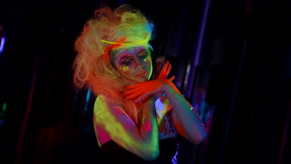 Actress with Fluorescent Makeup and Hairstyles Woman in UV Light in Darkness