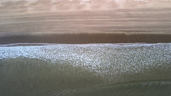 waves at low tide rolling in to black sand beach