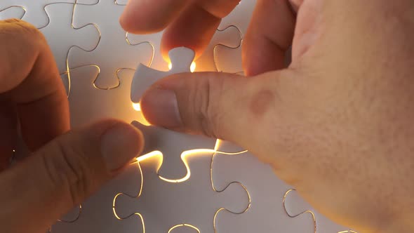 A man hand solve the last piece of white jigsaw puzzle.