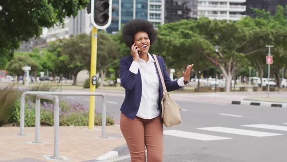 Smiling african american businesswoman walking and talking on smartphone