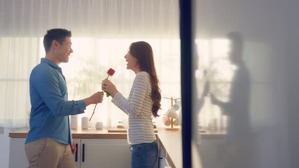 Asian young man surprise and give rose flower to beautiful girlfriend.