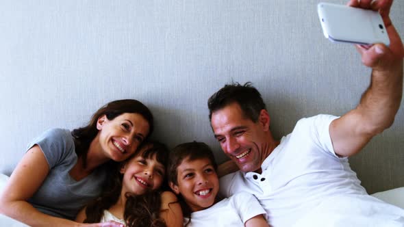 Happy family taking a selfie on bed in bedroom