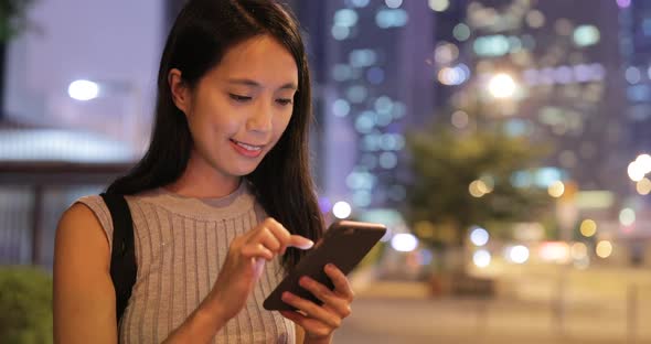 Woman using mobile phone in city at night 