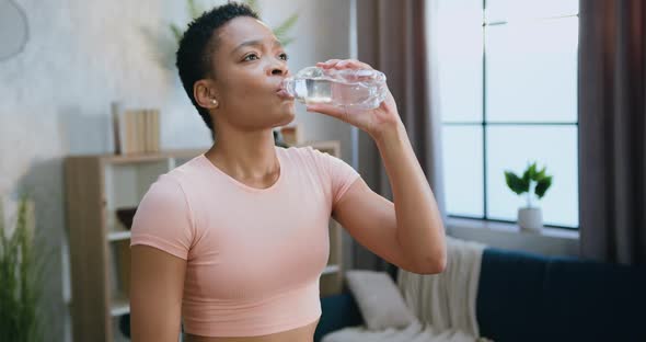 Woman in Light Pink Top which Drinking Water During Exercising on Running Track at Home