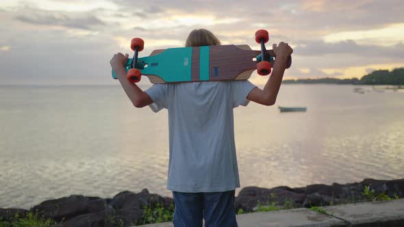 Portrait Boy with a Longboard on a Beautiful Road