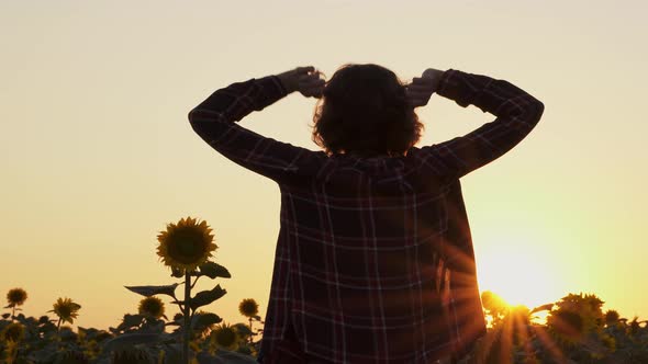 Happy Girl In Rays Of Setting Sun Raises Her Hands Up. Young Woman Is A Winner. Farmer, Agronomist