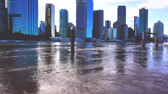 A view from across a very fast flowing river of a modern city during heavy rain