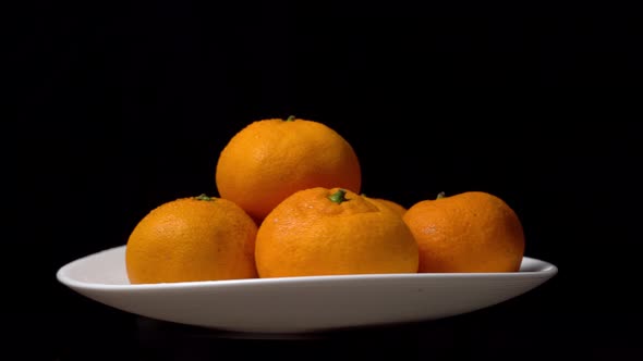 close-up of tangerines spinning on a turntable on a plate on a black background