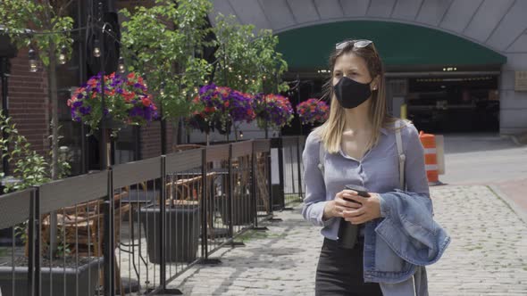 Young woman gets fresh air after corona lockdown wears mandatory black face mask