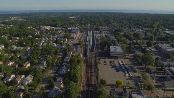 Train Stopped at Station and Small Town in Long Island Aerial View