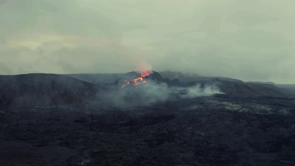 Drone shot towards magma fields and erupting craters in gloomy Iceland - approaching, Aerial view