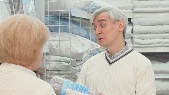 Senior Man Choosing Bedding Goods with His Wife at Furnishings Store