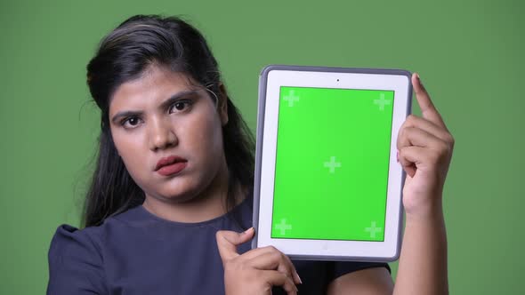 Young Overweight Beautiful Indian Businesswoman Against Green Background