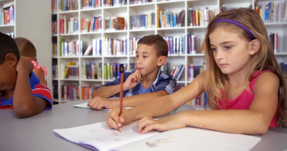 School kids drawing in book in classroom