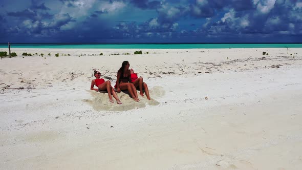 Modern smiling girls relaxing spending quality time at the beach on clean white sand and blue backgr