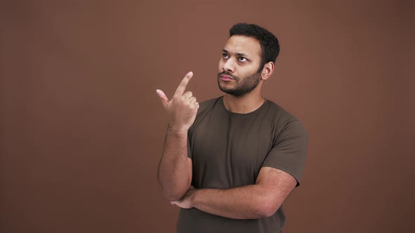 Pensive Indian Man Comparing Variants Counting on Hand and Thinking Brown Studio Background