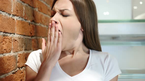 Yawning Tired Young Woman Sitting in Office