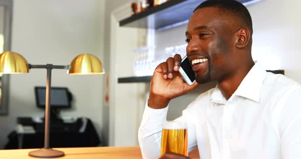 Man talking on mobile phone while having beer at counter