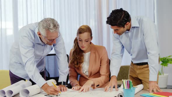 Businesswoman and coworkers discussing blueprint