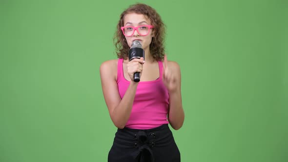 Young Happy Beautiful Nerd Woman Presenting Something with Microphone