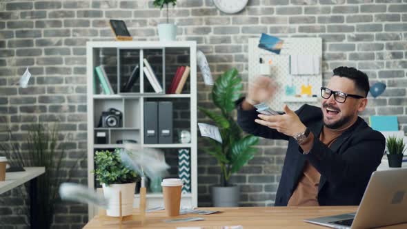 Excited Guy Throwing Money Laughing Enjoying Wealth in Office Alone