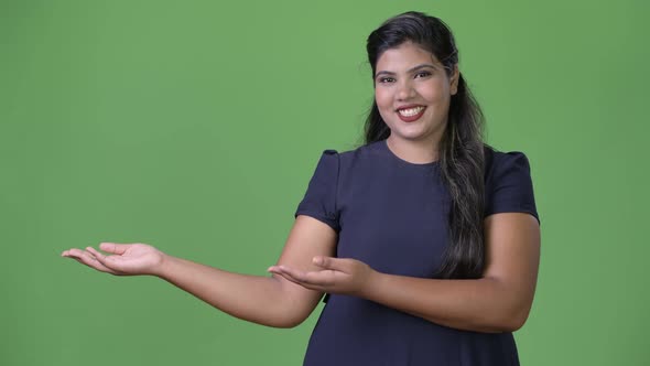 Young Overweight Beautiful Indian Businesswoman Against Green Background