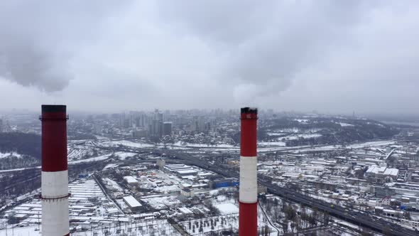 Aerial Observation of Snowy Industrial City with Two Huge Smoking Factory Pipes at the Foreground alt