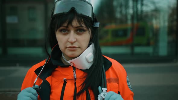 Tired Female Paramedic with Lowered Respirator Looks at you