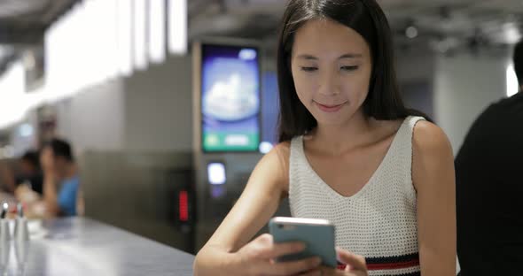 Woman Using Mobile Phone in Coffee Shop at Night 