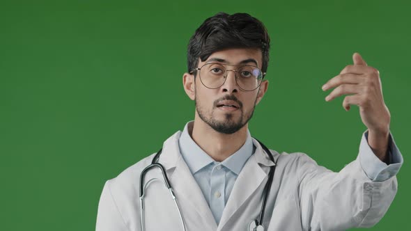 Indian Professional Male Doctor Arabian Man Doctor Intern in White Medical Uniform Stands in Green