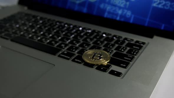 Dolly shot of Bitcoin BTC cryptocurrency. Golden coin on laptop keyboard