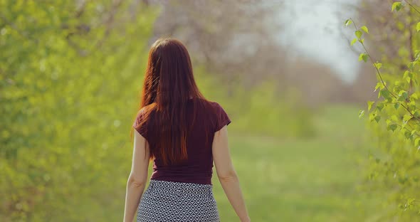 Young Brunette Woman Walks Through the Woods on a Sunny Afternoon