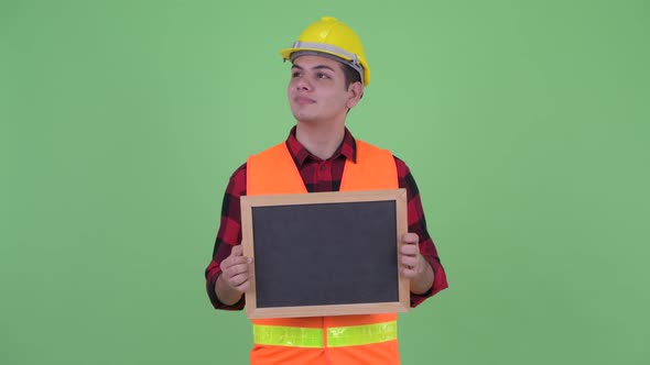 Happy Young Multi Ethnic Man Construction Worker Thinking While Holding Blackboard