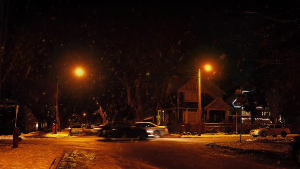 Cars Passing Houses At Night In Snowfall