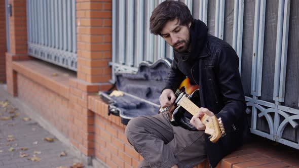 Guy Playing on the Giutar on the Street with Enthusiasm