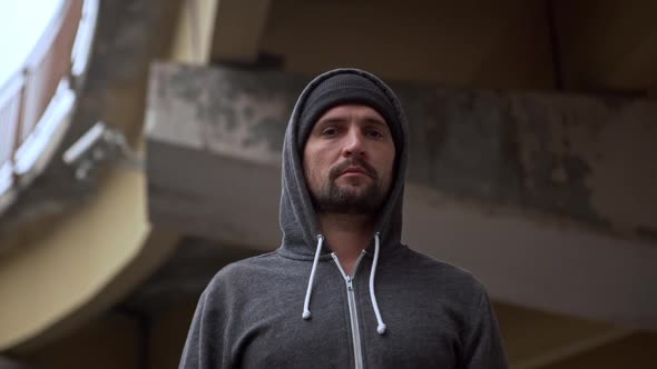 Round Footage From Beneath Serious Calm Handsome Man Wearing Hat and Grey Hoodie Standing Under