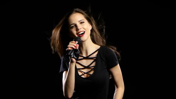 Singer Sings Energetic Songs, Her Hair Is Fluttering in the Wind. Black Background