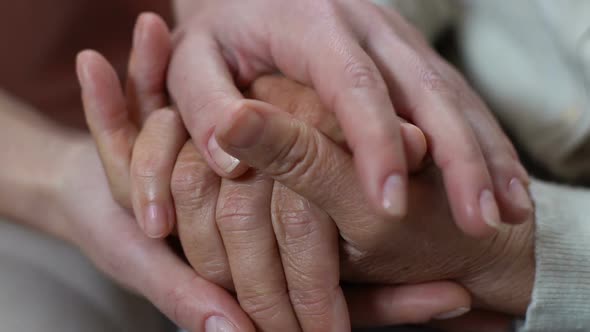 Young Woman Stroking Hands of Pensioner, Caring for Old Parents, Compassion