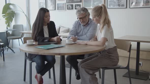 Female Advisor Helping Clients To Complete Document