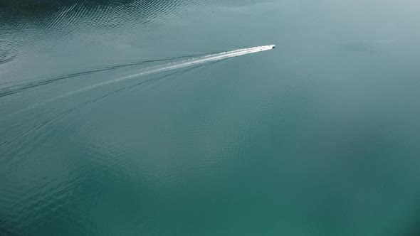 Aerial view of a white boat in the blue clear waters. Drone view of a yacht sailing to the blue sea.