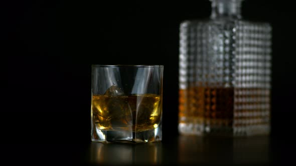 Close Up Shot of Whiskey in Transparent Glass and Bottle with Black Background