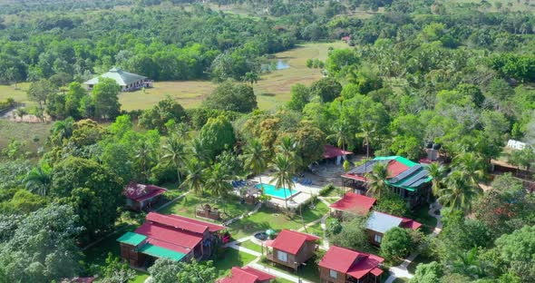 Aerial flyover of red roof buildings and green tropical landscape of hotel ecologico Loma Pan de Azu