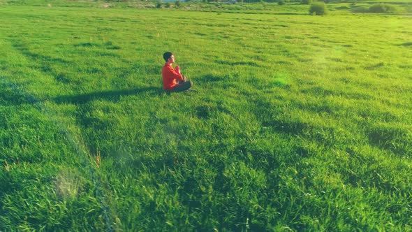 Low Altitude Radial Flight Over Sport Yoga Man at Perfect Green Grass. Sunset in Mountain.